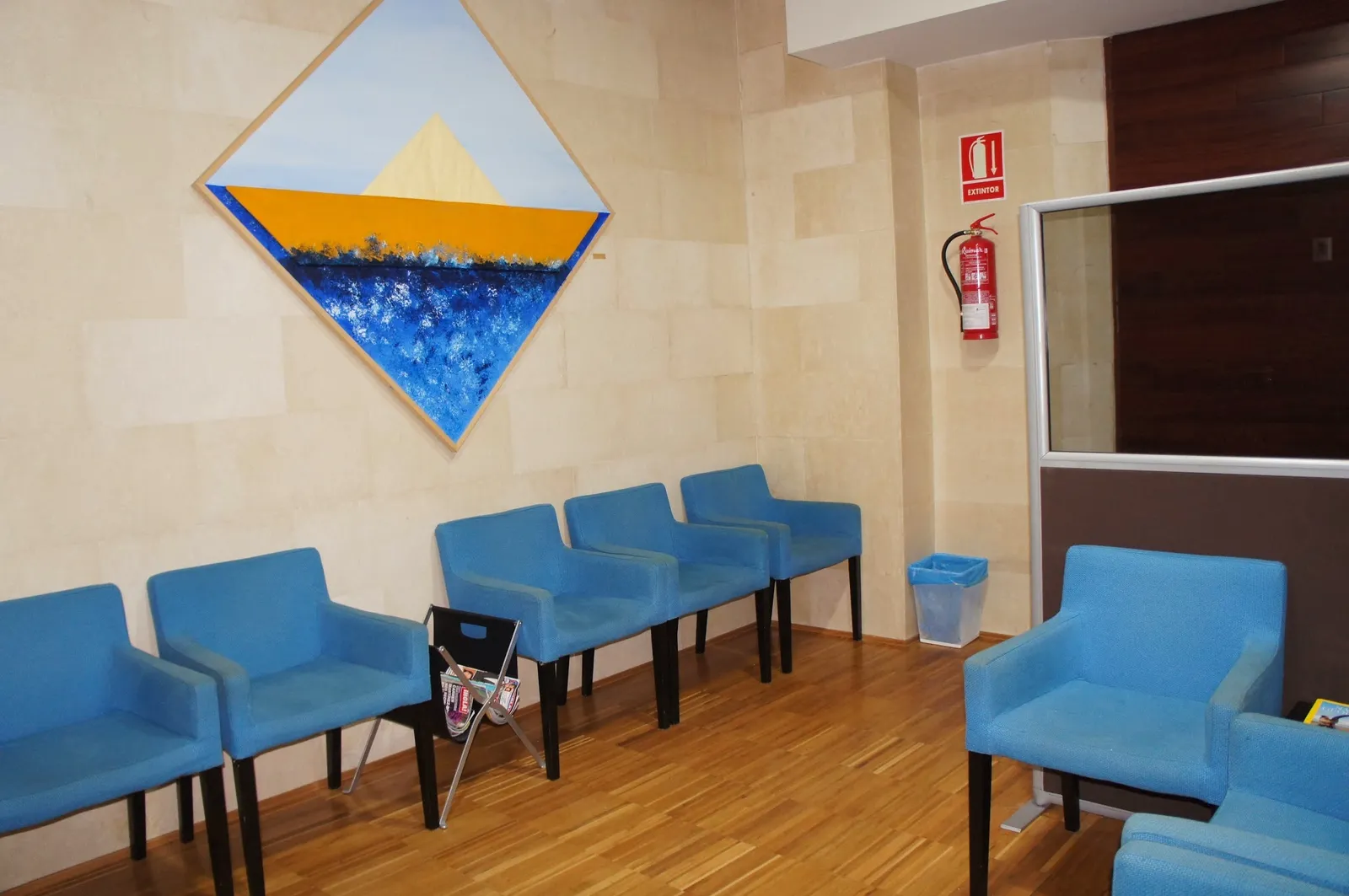 Sala de espera con sillones azules y un cuadro del mar en forma de rombo